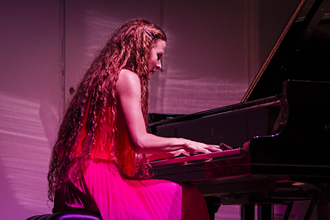 Woman in a red dress playing the piano on stage