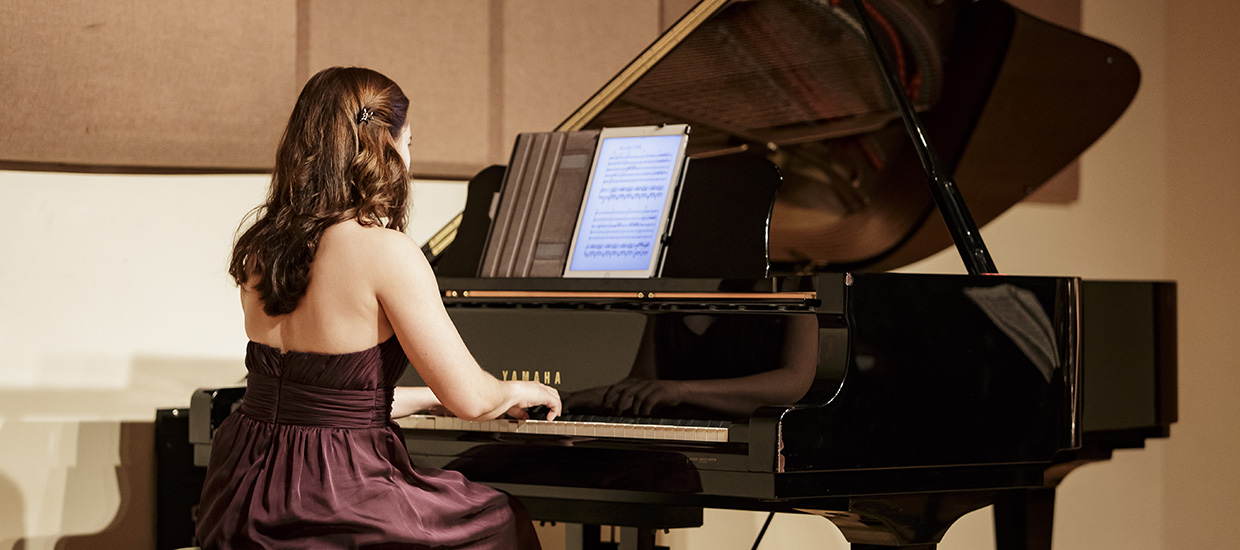 Woman in a red dress sitting down and playing the piano